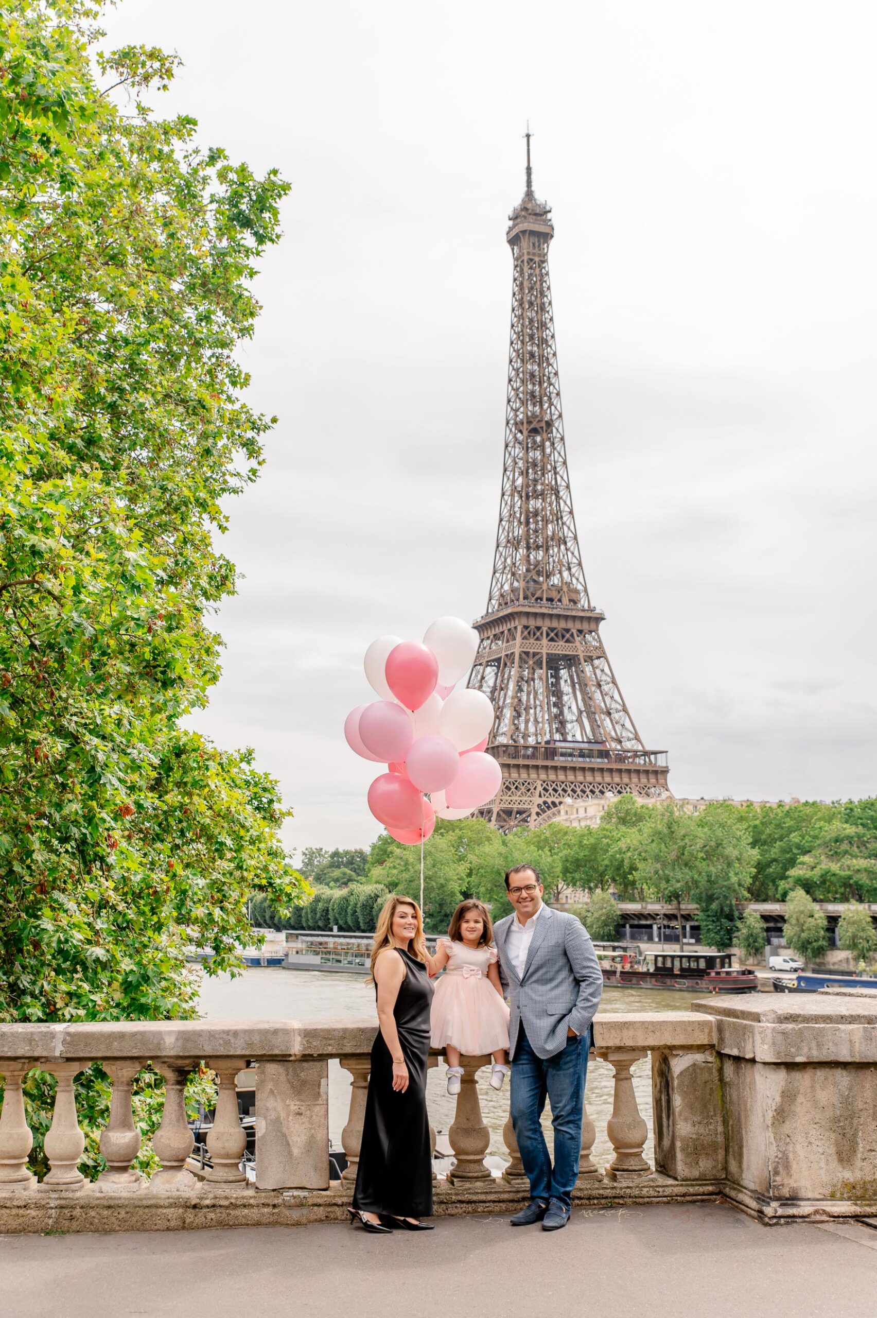 Family at Bir-Hakeim bridge with child holding balloons during Paris family photoshoot