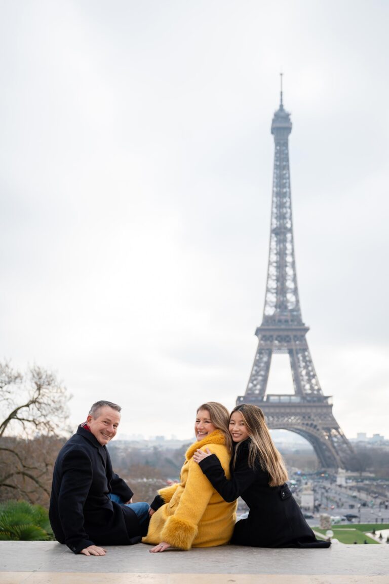 Family of three sitting at Trocadéro during winter Paris photo session with Eiffel Tower
