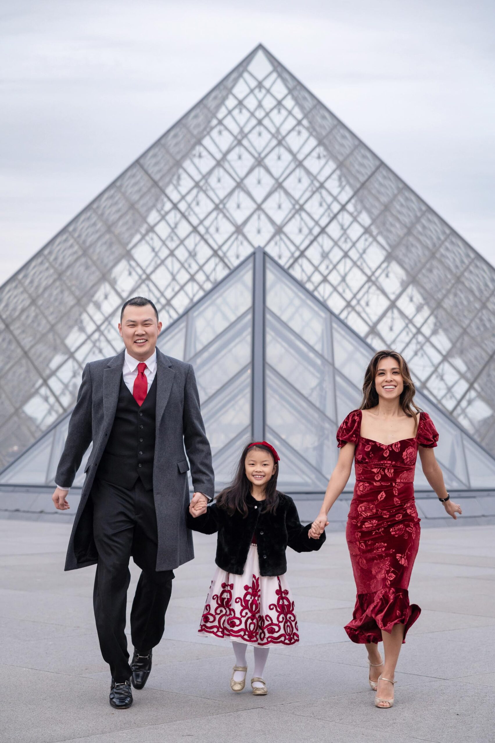 Family moment at the Louvre with child holding parents hands during Paris photoshoot